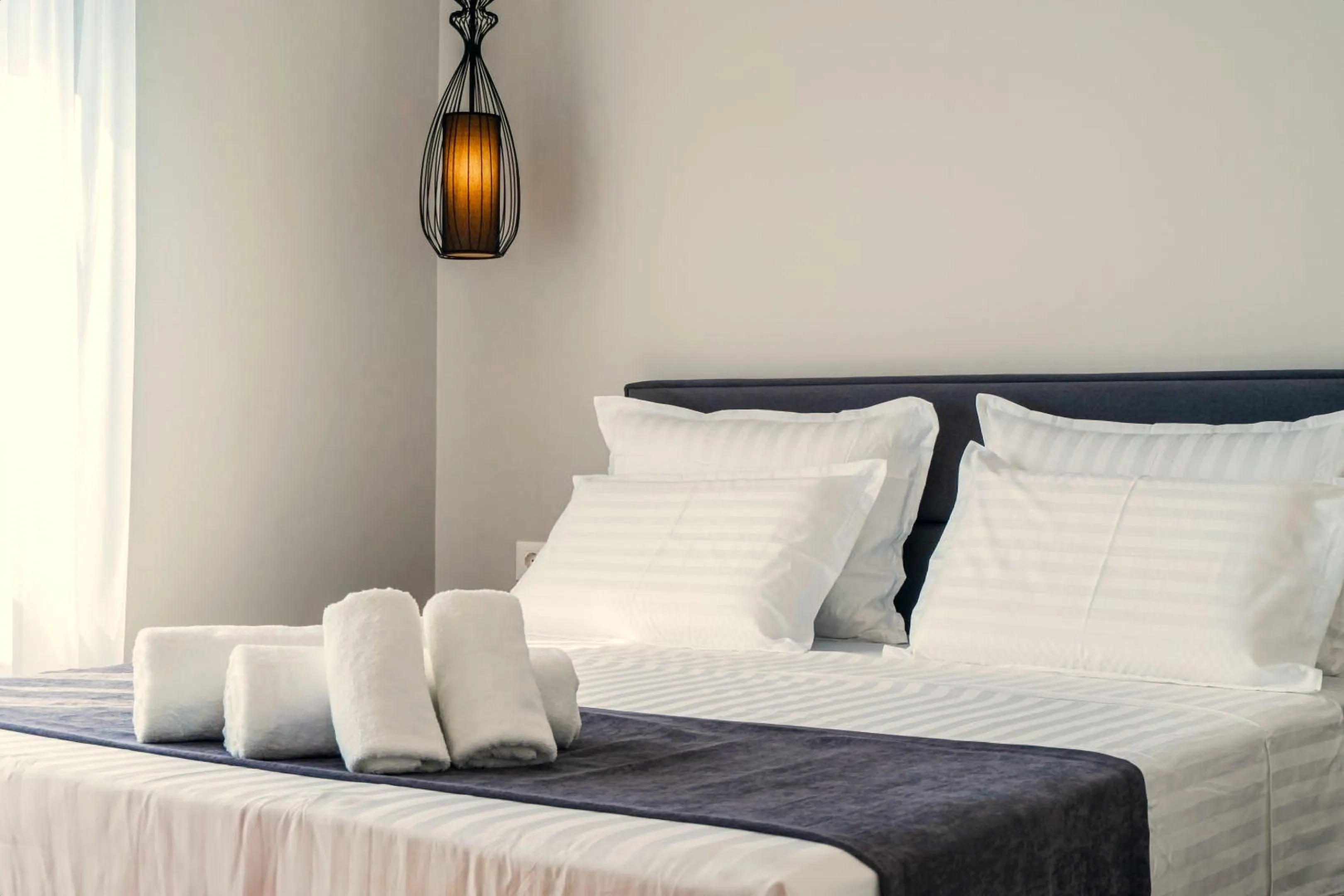 The queen bedroom with white linen and a pendant light